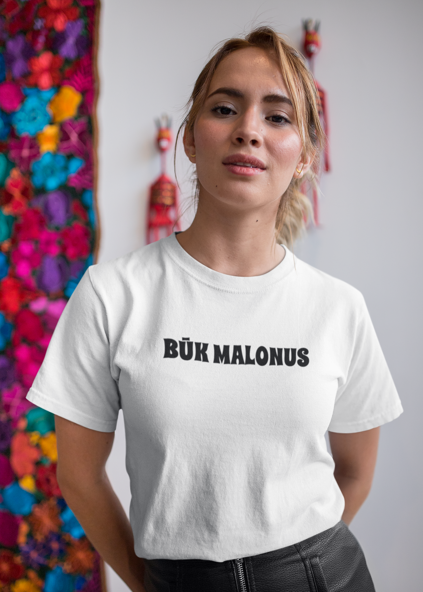 Moteris dėvinti lietuviškos tematikos baltus marškinėlius, kuriuose yra juodos spalvos užrašas "BŪK MALONUS".