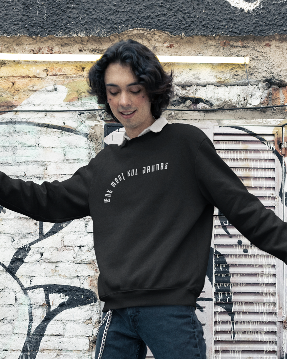 Pozuojantis modelis apsivilkęs šiuolaikišku jaunimo stiliaus juodu džemperiu su lietuvišku posakiu "Lenk medį kol jaunas"