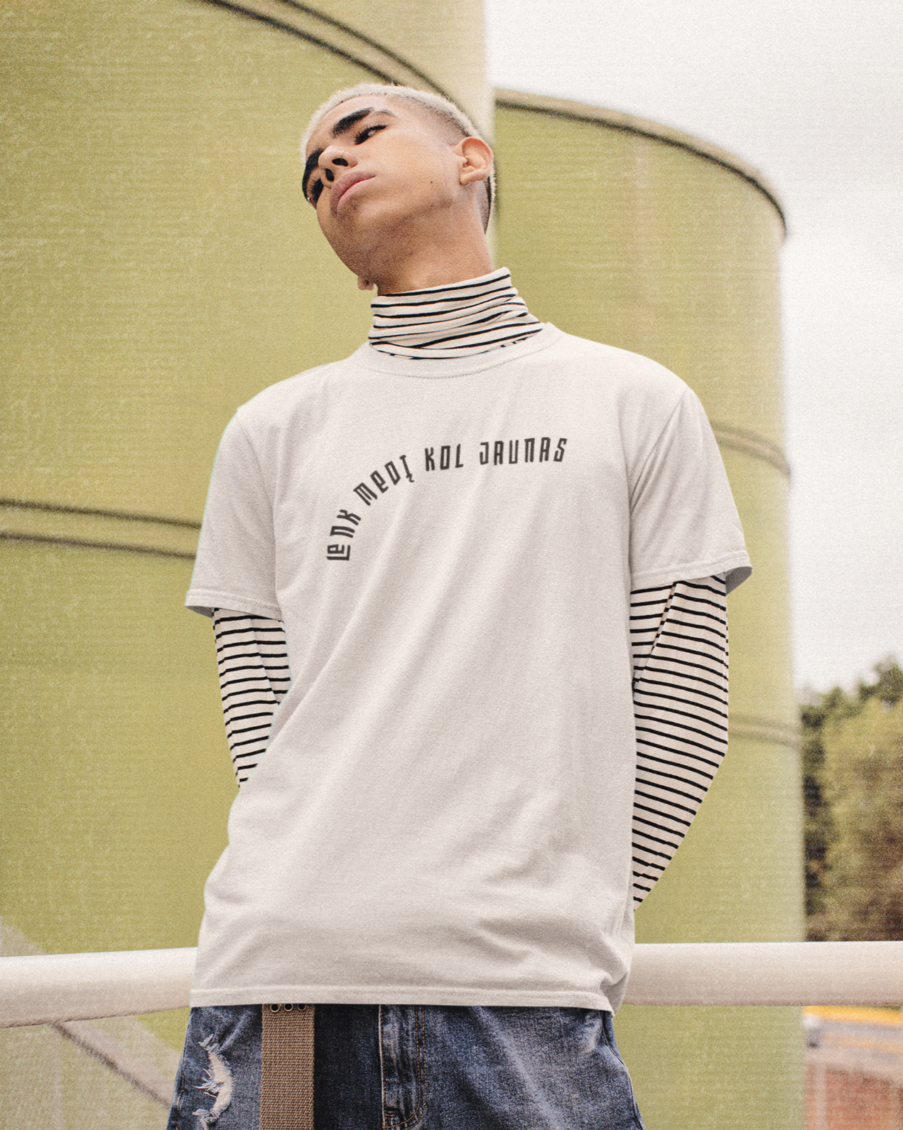 Jaunuolis dėvi baltus marškinėlius su užrašu - Lenk medį kol jaunas, kuriais išreikštas kūrybiškas požiūris į gatvės madą