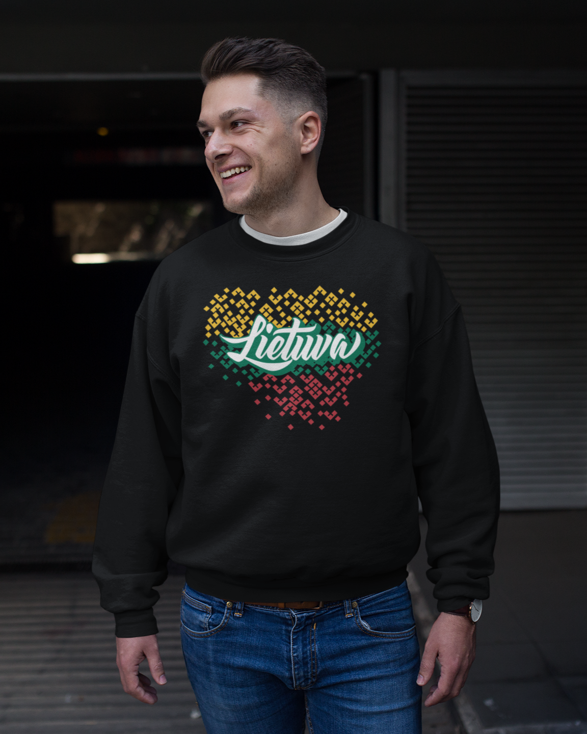 Vyras pozuodamas šypsosi, dėvi tautinės atributikos juodą džemperį su užrašu "Lietuva" ir spalvingu šalies kontūro motyvu