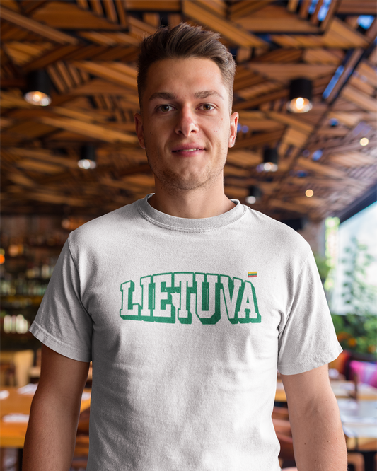 Vyras restorane, dėvi baltus marškinėlius su stilizuotu užrašu „LIETUVA“ iš lietuviškos tautinės atributikos kasdienai