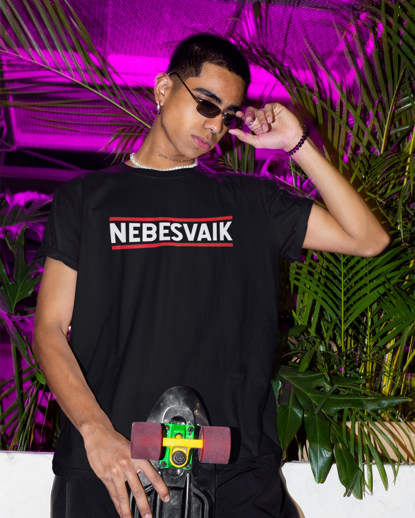 Jaunuolis dėvi juodus marškinėlius su užrašu NEBESVAIK, jaunatviško urban stiliaus su neoninio apšvietimo fone