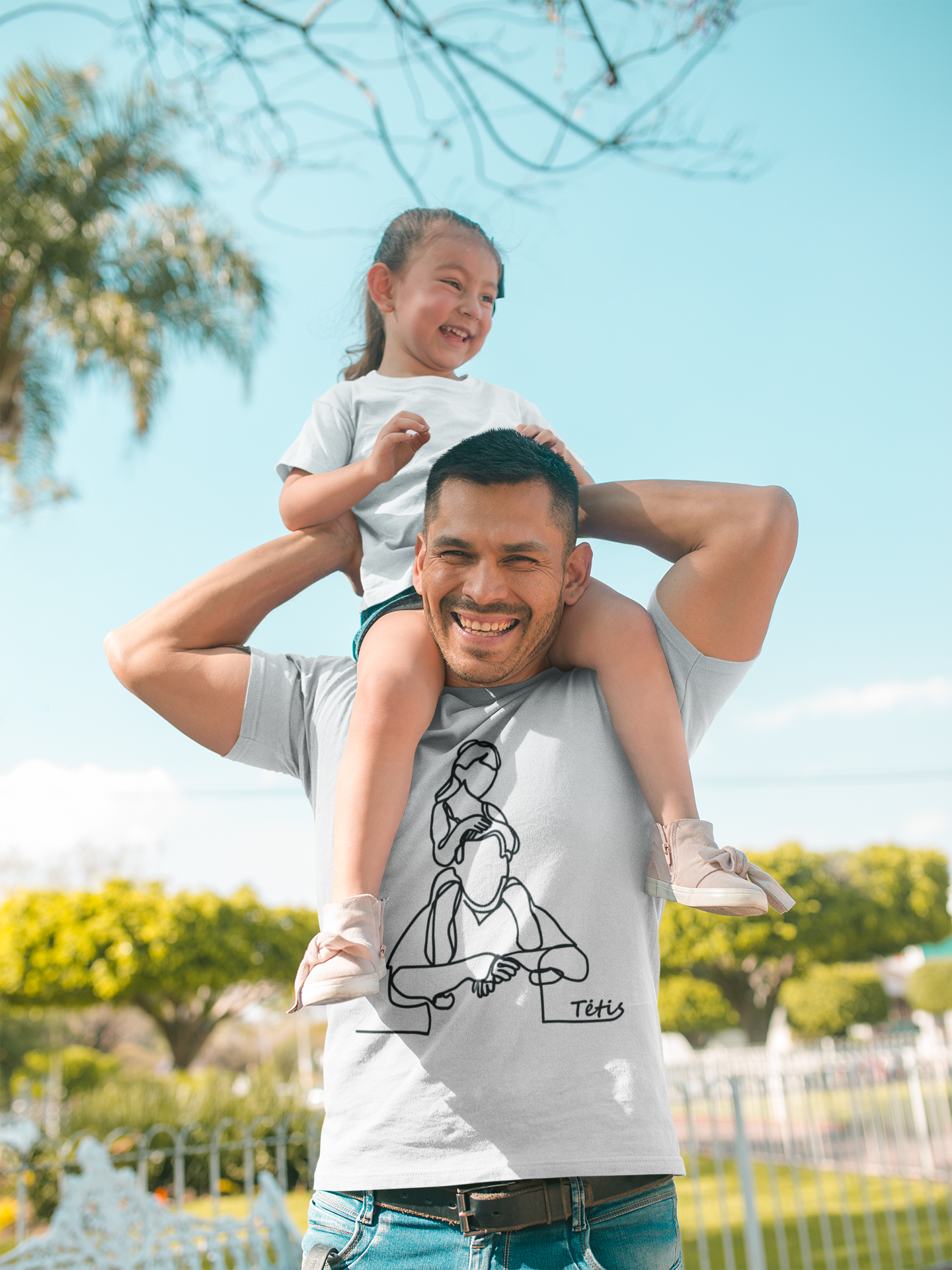 Tėvas su dukra ant pečių vilki baltus tėvo dienos marškinėlius su linijine iliustracija, vaizduojančia tėtį su mergaite.