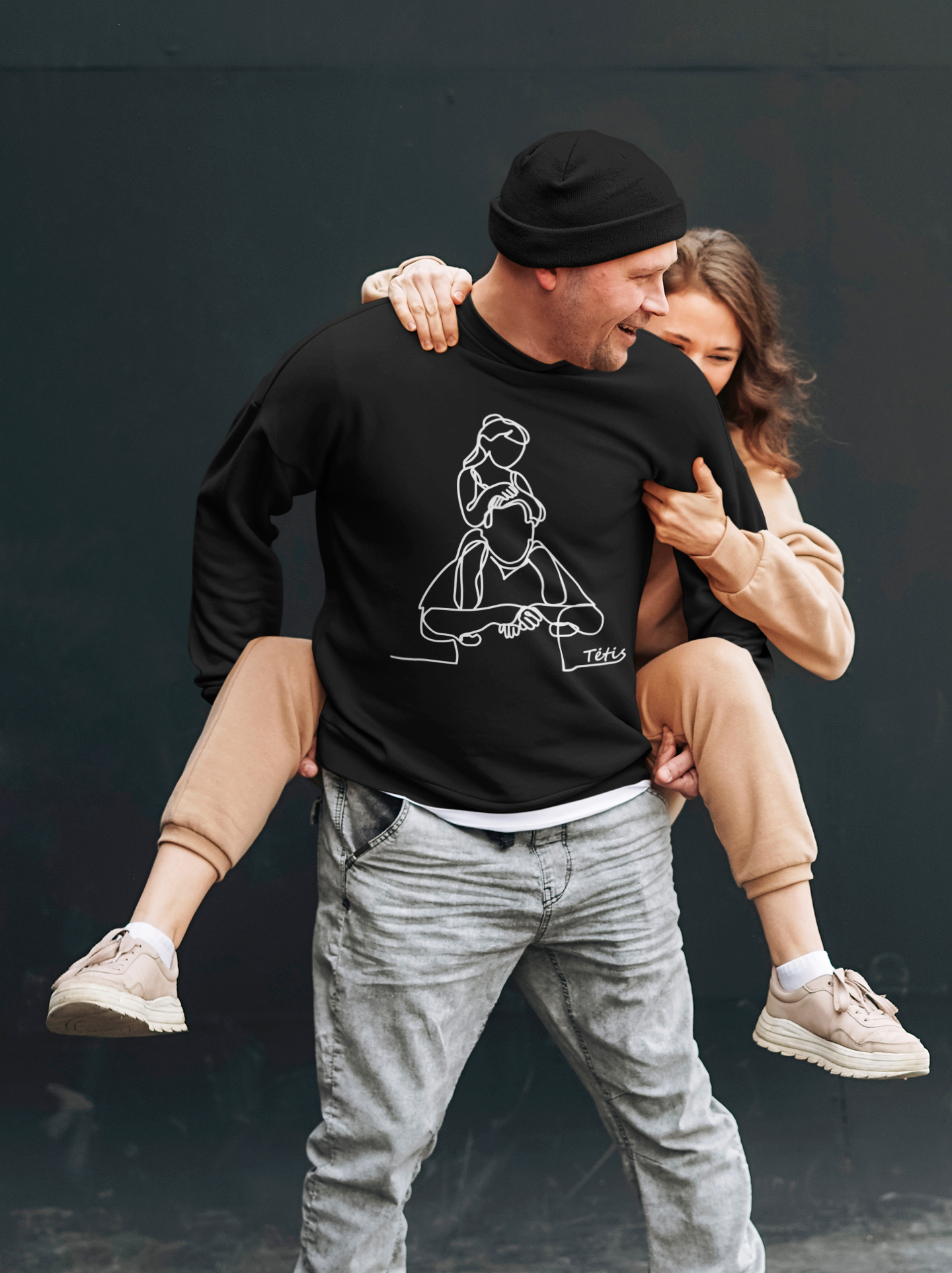 Vyras su juodu džemperiu, su baltu linijiniu piešiniu – tėčio ir dukros siluetais. Prasmingas ir stilingas drabužis tėvui.