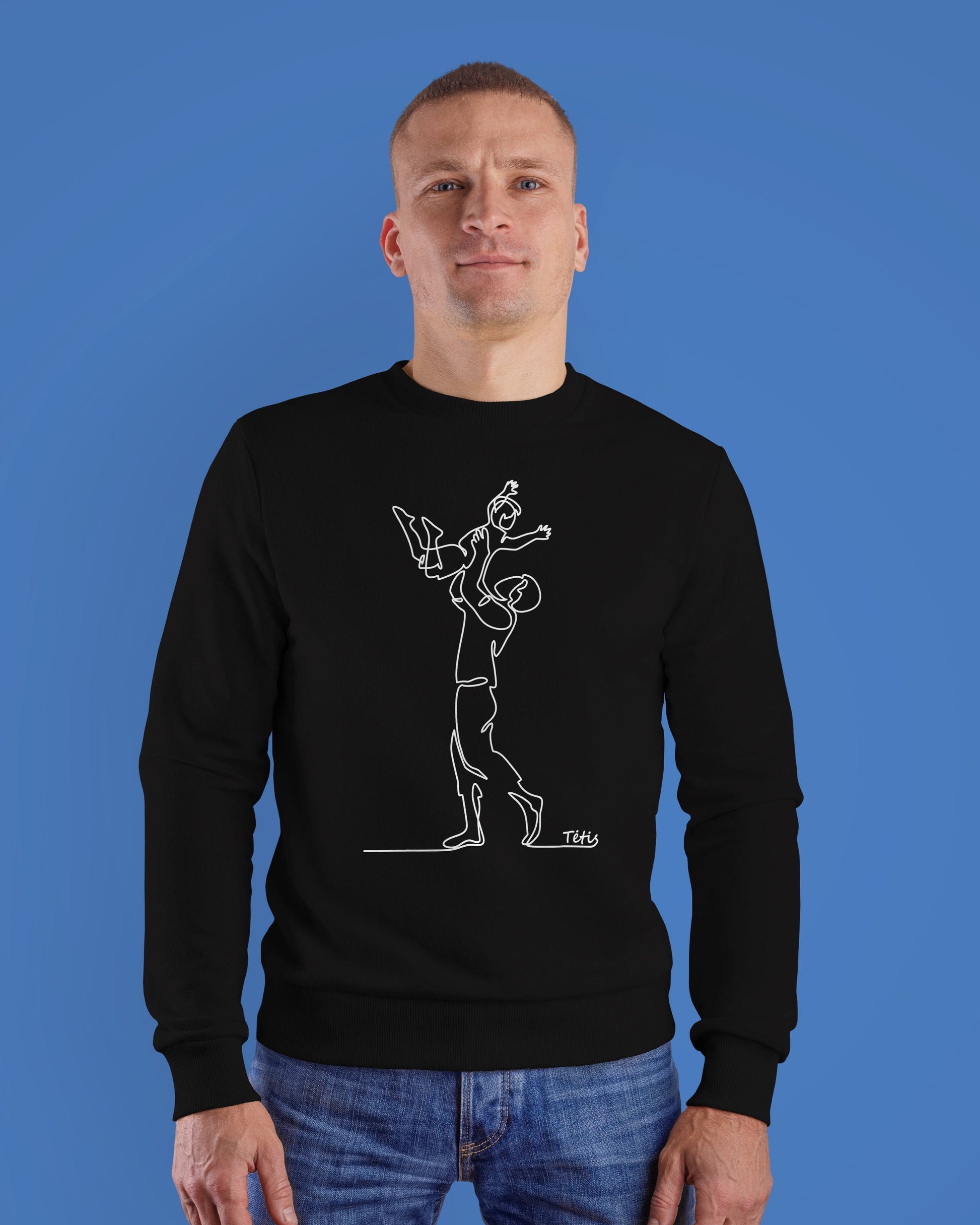 Vyras apsirengęs juodą džemperį, kuriame linijine grafika pavaizduotas tėtis iškėlęs sūnų ant rankų ir mini užrašas "Tėtis".