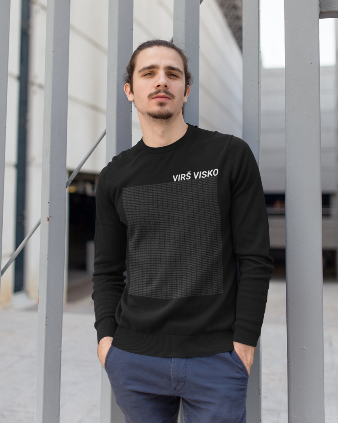 Jaunatviškas vyras dėvi juodą džemperį su lietuviškos tematikos tekstiniu dizainu ir lietuviška fraze "Virš visko".