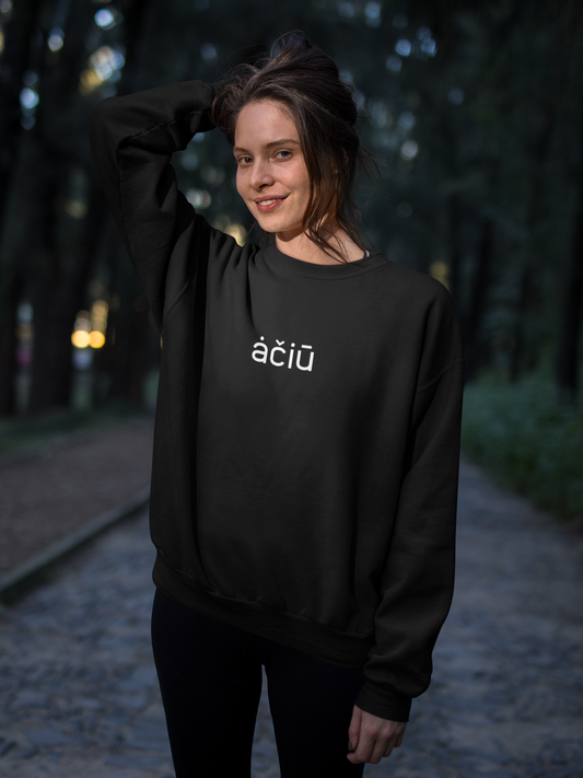 Moteris parke su lietuviškos tematikos juodu džemperiu su užrašu „ačiū“  – stilinga apranga su subtilia lietuviška žinute.