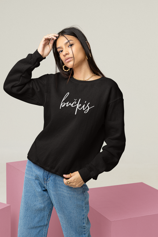 Modelis pozuoja vilkėdama juodą džemperį su baltu ranka užrašytu užrašu „bučkis“ – akcentas madingai tautiškai aprangai.